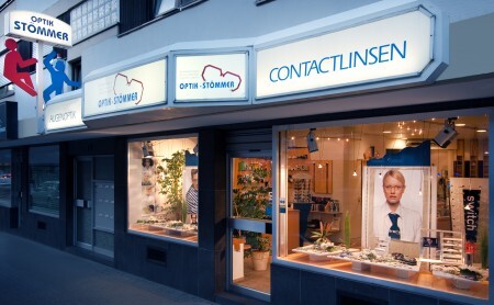 Fassade eines Optikers mit Schaufenster, Kontaktlinsenwerbung und moderner Ladeneinrichtung.